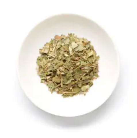 Witch hazel leaves sitting in a white bowl on a white background