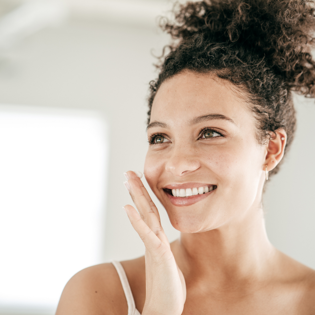 Image of a happy woman applying the Envio acne cleanser to her skin